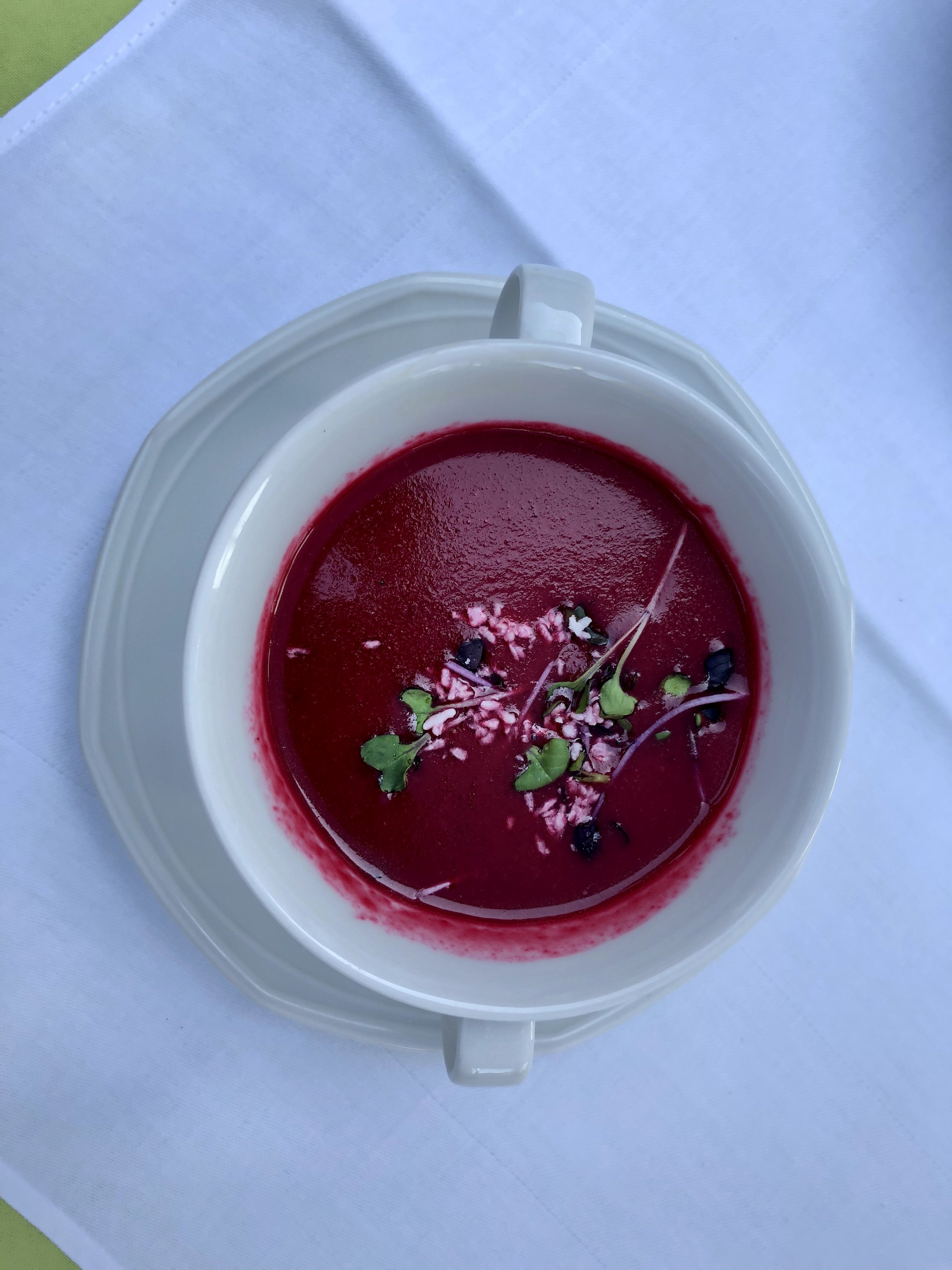 Rote-Bete-Suppe in weißem Suppenteller auf weißer Tischdecke.
