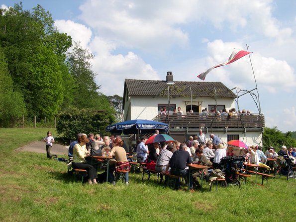 Weinbergshäuschen im Hintergrund, im Vordergrund feiernde Menschen 
