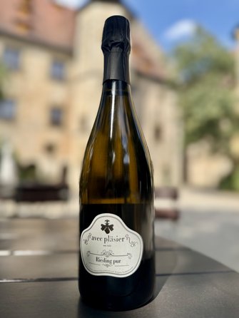 Eine Flasche des vielfach ausgezeichneten Sektes Riesling Pur vom Weingut Schloss Sommerhausen steht auf einem Tisch im Schlosshof. 
