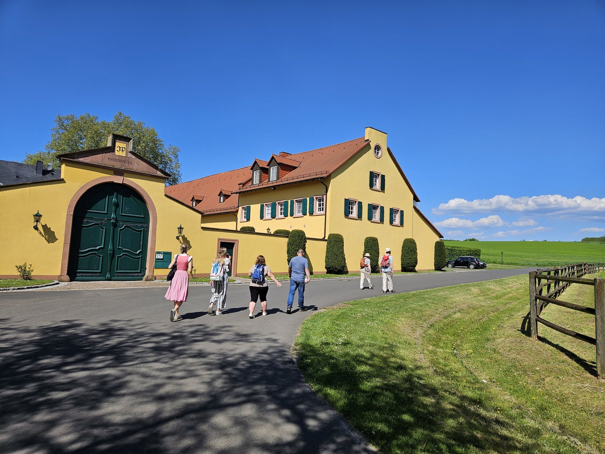 Wandergruppe vor einem gelben Herrenhaus.