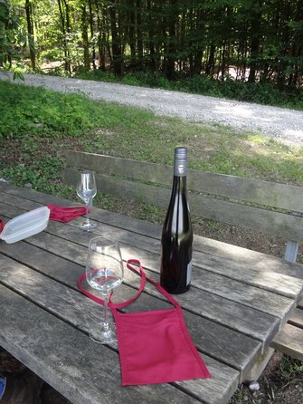 Stilweinglas und Weinflasche auf Holztisch im Wald.