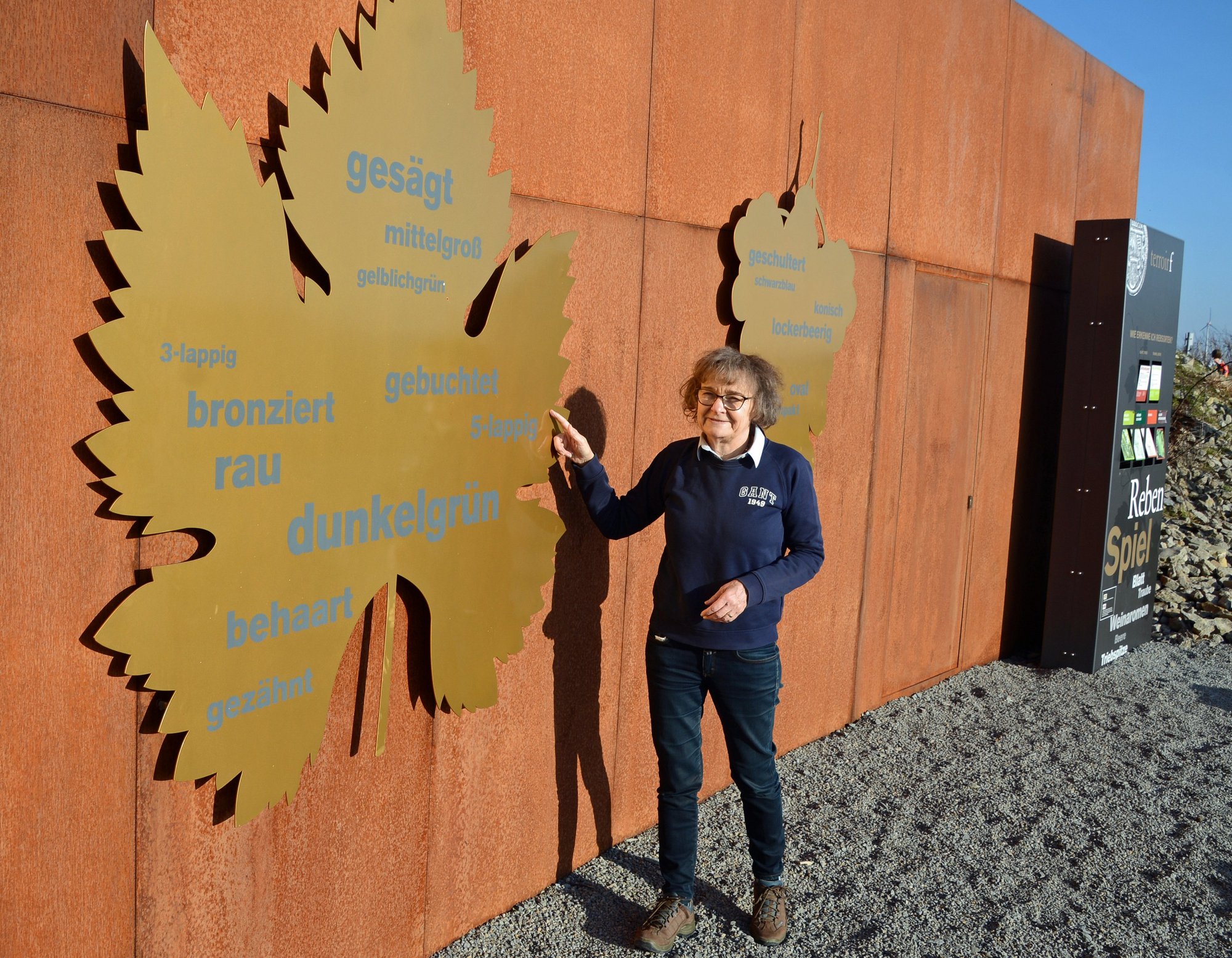 Auf dem Bild ist die Gästeführerin Gabriele Brendel zu sehen, die am terroir f in Eibelstadt die Form eines Weinblatts erklärt. 