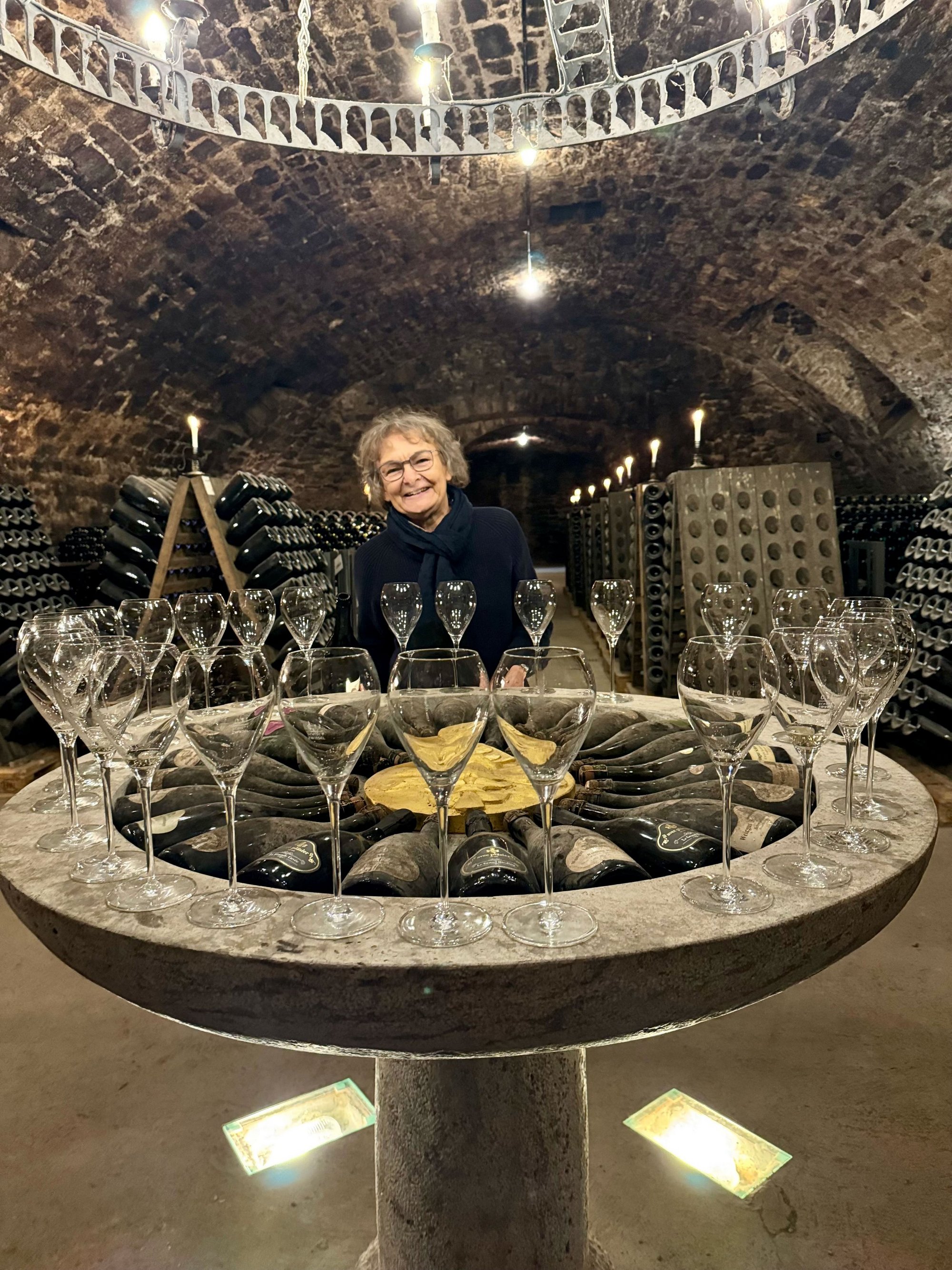 Gabriele Brendel steht im Sektkeller vom Weingut Schloss Sommerhausen vor einem brunnenartigen Kunstwerk, auf dem viele leere Sektgläser stehen.